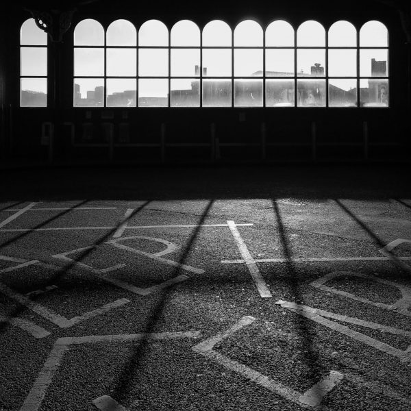 Silhouette of a row of arched windows, with abstract letters painted on the ground in front