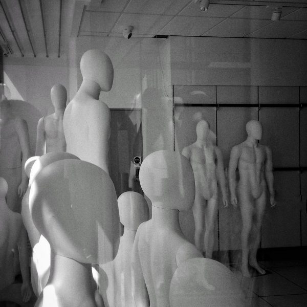 Black and white photo of a group of undressed mannequins standing inside an empty shop