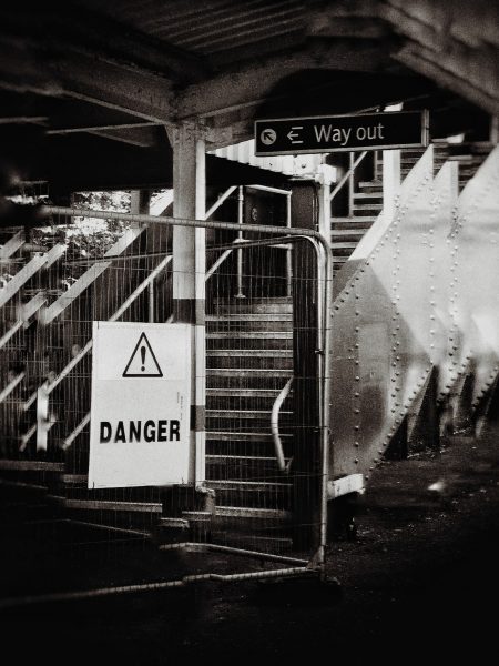 Black and white photo of a staircase, with a sign at the top saying 