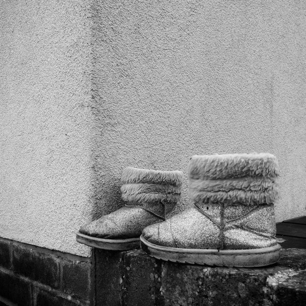 Black and white photo of two fluffy kids boots on a wall