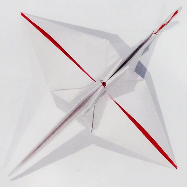 Abstract photo of intersecting diagonal lines, mostly white and grey, with some red. On closer inspection, it is the underside of an origami crane.